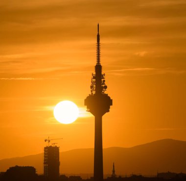 Güneşin batışı neredeyse bir iletişim kulesine dokunuyordu. Madrid 'in gökyüzünde turuncu tonlarda bulutlar....