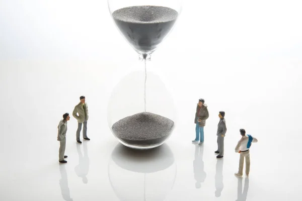 miniature people. people of different ages and statuses stand in line near the hourglass. the concept of the importance of time and life