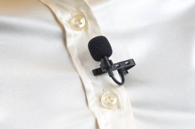 Lavalier mikrofon yakın plan kadın gömleğinin klipsiyle korunuyor. Yoğunlaştırıcı mikrofondaki sesin ses kaydı.