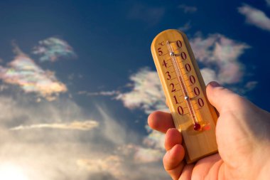 Sıcak yaz havasında gökyüzünün arka planına karşı doğadaki sıcaklığı ölçmek için termometre