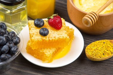 Farklı çeşitlerde taze çiçek balı, polen ve ahşap arka planda kaşıkları olan bal peteği. Organik Vitamin Sağlıklı Gıda