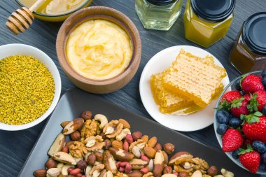 Tahta arka planda taze bal, fındık, çilek ve yaban mersini. sağlıklı organik vitamin yiyeceği.