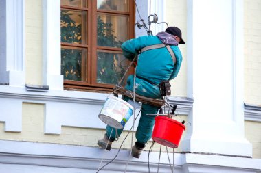 Camları temizleyen dağcı işçisi ve yenilenmiş bir konut binasının ön cephesi. inşaat sektörü