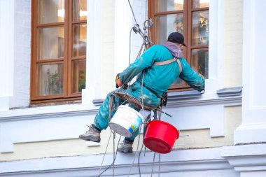 Tırmanış işçisi pencereye ve onarımda olan bir binanın ön cephesine hizmet ediyor. inşaat sektörü