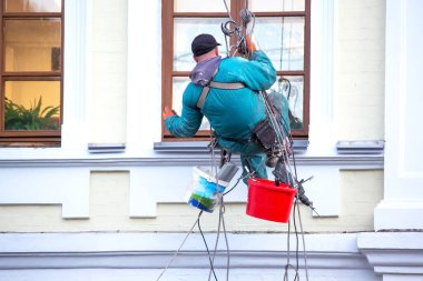 Tırmanış işçisi bir binanın ön ve penceresini tamir ediyor. inşaat sektörü