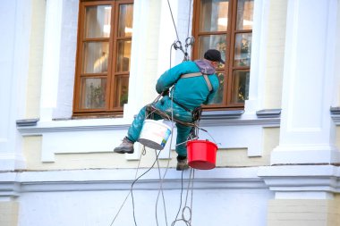 Tırmanış işçisi bir binanın ön ve penceresini tamir ediyor. inşaat sektörü