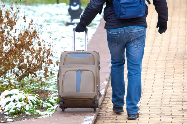 man walking down the sidewalk with a luggage bag