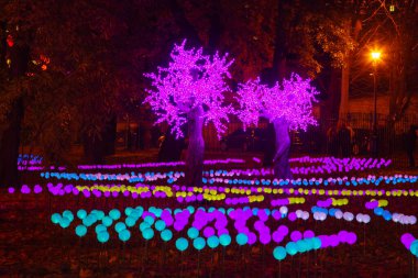 Şehir parkında parlayan renkli çelenkler. sokak ışığı renk festivali dekorasyonu