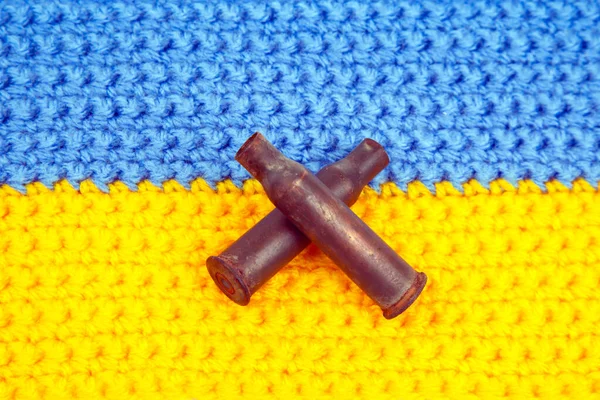 used cartridge cases from a machine gun cartridge against the background of the Ukrainian flag. war in Ukraine. Russian aggression against Ukraine