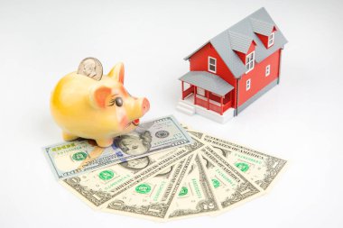 piggy bank for money and a house model with dollars on a white background. buying a property. the concept of buying and selling houses and apartments