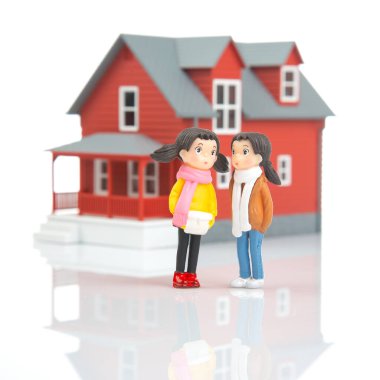 miniature people. romantic couple of young people near the house model on a white background. friendship and great relationship