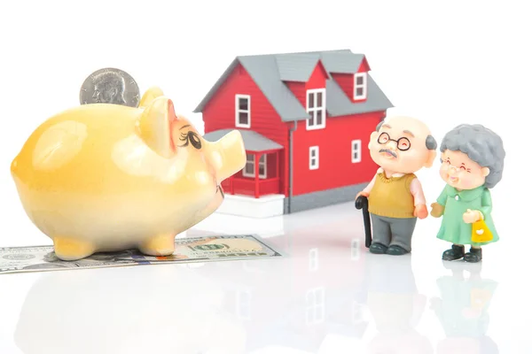 stock image piggy bank for money and a model of a house with pensioners. buying a property. the concept of buying and selling houses and apartments