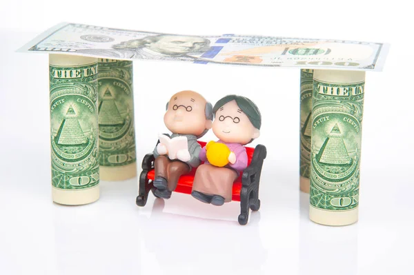 miniature people. a couple of pensioners under the house of dollars. financial security and pension for the elderly. concept of financial independence