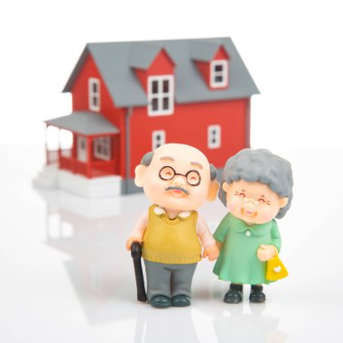 miniature people. a couple of retired people near the house model on a white background. financial security and pension for the elderly. concept of financial independence