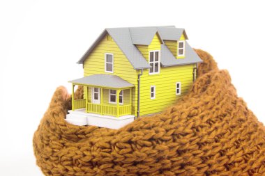 house model is insulated with a knitted scarf on a white background. the concept of keeping warm and cozy indoors at home. cold protection