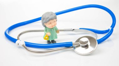 miniature people. Stethoscope and figurines of pensioners on a white background. The concept of health and disease prevention in the elderly