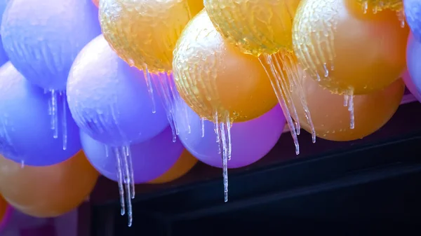 icicles on frozen colored inflatable holiday balls. winter weather season. street interior details