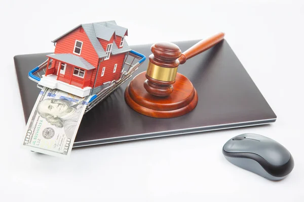 court hammer and auction on the background of a house model in a grocery basket and a laptop. legitimacy of real estate transactions. selling and buying a house