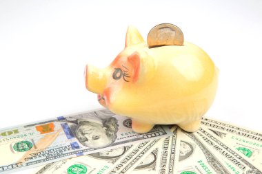 ceramic piggy bank for coins in the shape of a pig on the background of dollars. accumulation of finances and growth of monetary incomes. deposit and investment in business