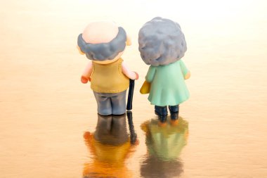 miniature people. figures for the concept. a couple of pensioners walk together. attitude and friendship in old age