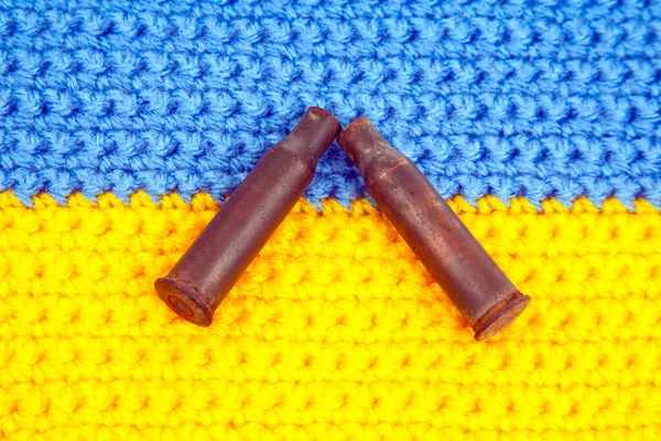 used cartridge cases from a machine gun cartridge against the background of the Ukrainian flag. war in Ukraine. Russian aggression against Ukraine