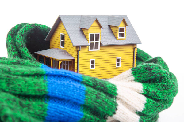 модель дома изолирована вязаным шарфом на белом фоне. концепция сохранения тепла и уюта в доме. холодная защита