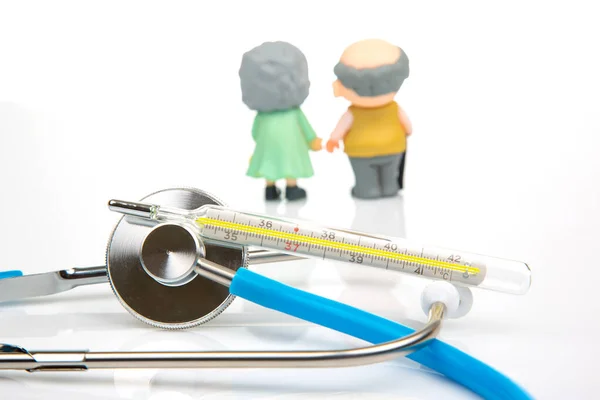 miniature people. Stethoscope and figurines of pensioners on a white background. The concept of health and disease prevention in the elderly