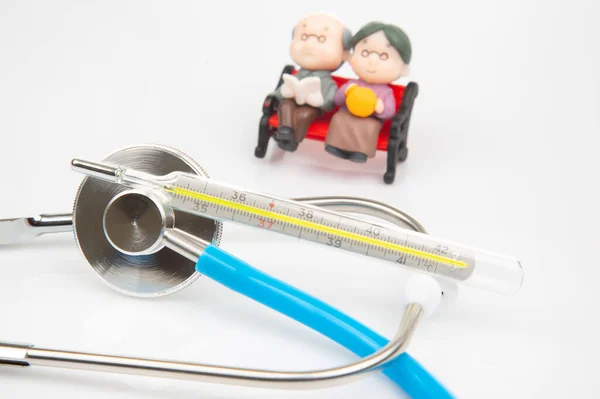 miniature people. Stethoscope and figurines of pensioners on a white background. The concept of health and disease prevention in the elderly
