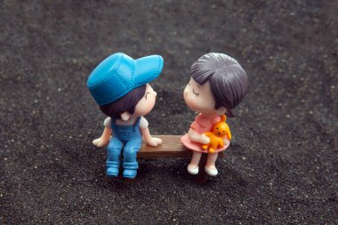 miniature people. figures for the game. romantic couple of young people. Boy and girl sitting on a bench