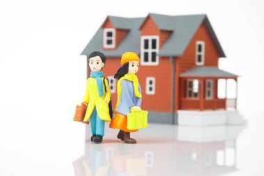 miniature people. romantic couple of young people near the house model on a white background. friendship and great relationship
