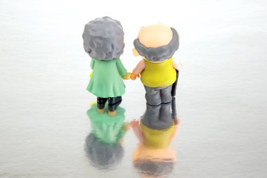 miniature people. figures for the concept. a couple of pensioners walk together. attitude and friendship in old age