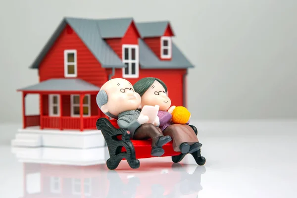 miniature people. a couple of retired people near the house model on a white background. financial security and pension for the elderly. concept of financial independence
