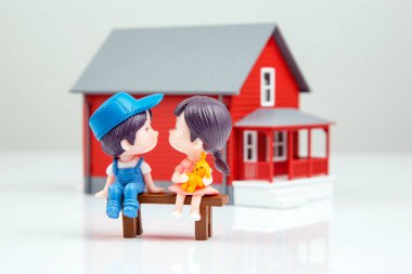 miniature people. romantic couple of young people near the house model on a white background. friendship and great relationship