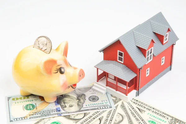 piggy bank for money and a house model with dollars on a white background. buying a property. the concept of buying and selling houses and apartments