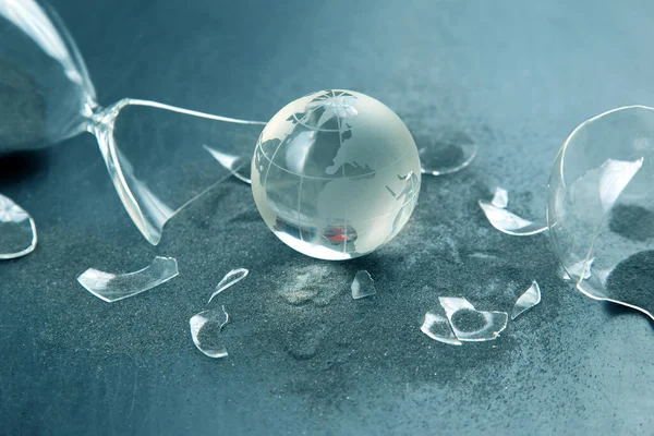 stock image glass model of the planet against the background of a broken hourglass. The concept of stopping time for the life of the earth