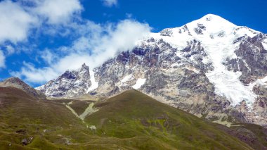 Yeşil çimenlerin ve karlı dağların manzarası. Gürcistan 'da seyahat ve seyahat