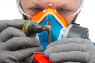 Erkek çilingir işçi, metali oymalı matkapla işliyor. Dremel oyma aletinin işi. Endüstriyel metal işleme endüstrisi