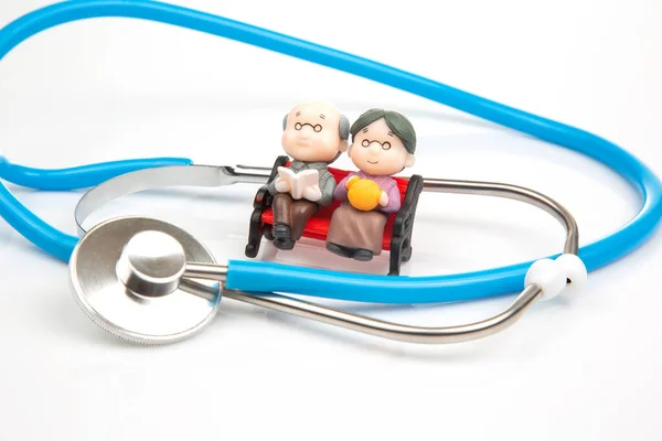 stock image miniature people. Stethoscope and figurines of pensioners on a white background. The concept of health and disease prevention in the elderly