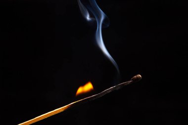 Karanlık bir arka planda yanıp tutuşan ahşap kibrit. Yanan bir ağaçtan gelen parlak ateş ve duman.