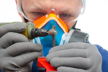 Erkek çilingir işçi, metali oymalı matkapla işliyor. Dremel oyma aletinin işi. Endüstriyel metal işleme endüstrisi