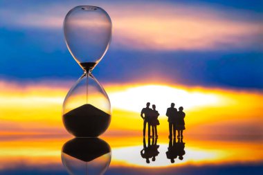 miniature people. silhouettes of different people watching the sunset next to the hourglass. end of life. clipart