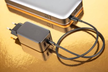 Güç bankası ve elektrik prizi, altın bir arka planda kablolu yayın. Cihazları şarj etmek için elektronik aygıtlar