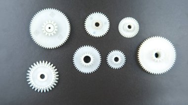 Siyah arka planda beyaz plastik dişliler. bağlantı mekanizması detayları. hareket konusu