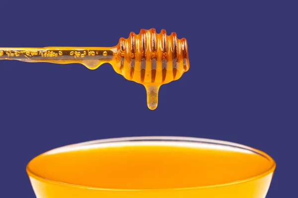 新鲜芬芳的蜂蜜从勺子滴在蓝色背景的盘子里 有机维生素营养 — 图库照片