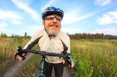 Sakallı bir bisikletçi doğada bir yolda bisiklet sürüyor. Spor, hobiler ve sağlık için eğlence