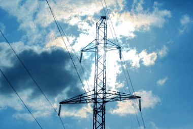 Güneş, gökyüzü ve bulutların arka planında elektrik kabloları olan yüksek voltaj kulesi. Elektrik kaynağı konsepti. Enerji endüstrisi.