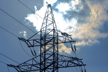Güneş, gökyüzü ve bulutların arka planında elektrik kabloları olan yüksek voltaj kulesi. Elektrik kaynağı konsepti. Enerji endüstrisi.
