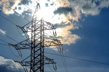Güneş, gökyüzü ve bulutların arka planında elektrik kabloları olan yüksek voltaj kulesi. Elektrik kaynağı konsepti. Enerji endüstrisi.