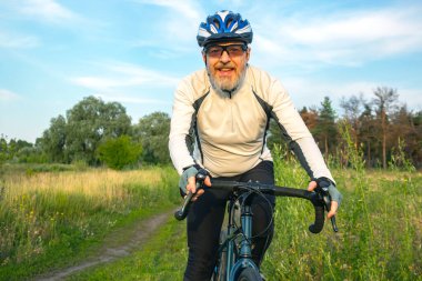 Sakallı bir bisikletçi doğada bir yolda bisiklet sürüyor. Spor, hobiler ve sağlık için eğlence