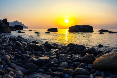 Taştan sahilde gün doğumu ve günbatımı. Doğadaki manzara